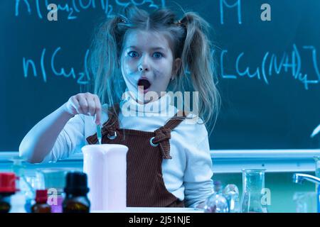 Mignonne petite fille mélange des produits chimiques pendant la leçon de chimie à l'école Banque D'Images