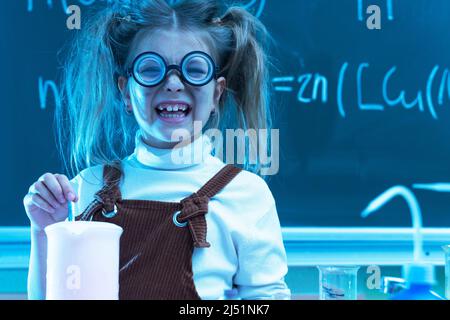 Mignonne petite fille mélange des produits chimiques pendant la leçon de chimie à l'école Banque D'Images