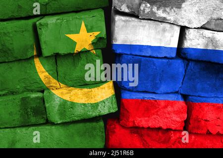 Concept de la relation entre la Mauritanie et la Russie avec deux drapeaux peints sur un mur de briques endommagé Banque D'Images