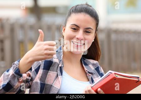 Vue de face d'un étudiant heureux qui fait un geste de pouce dans un parc Banque D'Images