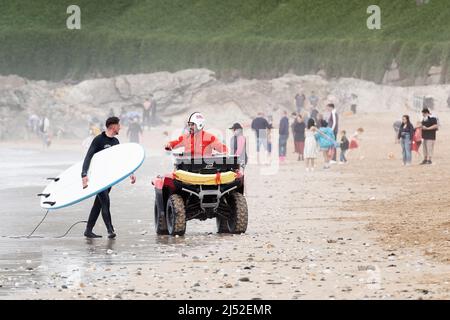 A RNLI Lifeguard offre des conseils à un surfeur sur une plage de Fistral, Newquay, Royaume-Uni. Les sauveteurs patrouillent sur des quads à l'endroit populaire de surf Banque D'Images