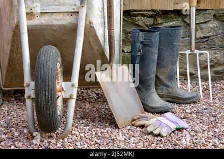 Articles de jardinage y compris brouette, grande pelle, grande fourche, gants et bottes en caoutchouc Banque D'Images