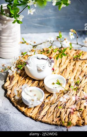 Théière asiatique et tasses avec thé vert et branches en cerisier Banque D'Images