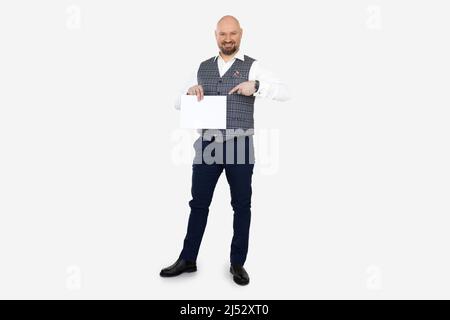 Homme d'âge moyen souriant, gilet à carreaux gris, Jean bleu, chemise blanche maintenez le doigt pointant sur une feuille de papier vierge. Banque D'Images