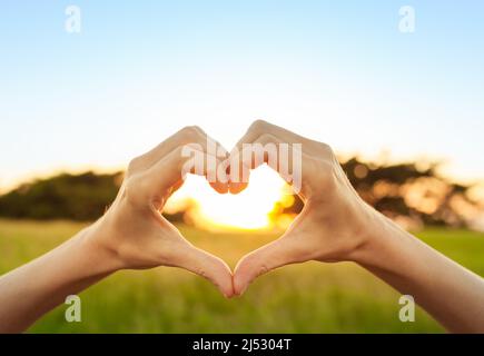 Coeur en forme de main sur fond de coucher de soleil nature Banque D'Images