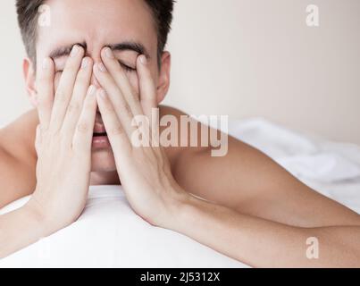 jeune homme au lit souffrant d'insomnie manque de sommeil, se sentant fatigué et malade Banque D'Images