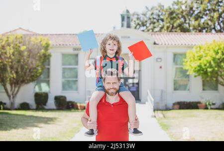 Père marchant fils à l'école. Les parents reçoivent un enfant de l'école une promenade en pigeyback. Style de vie familial. Banque D'Images