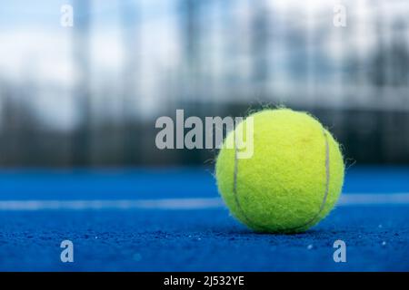 Ballon de tennis sur un court de paddle bleu, concept de sports de raquette Banque D'Images
