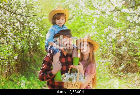 Une famille joyeuse pique-nique dans un parc. Agriculteurs familiaux travaillant dans le jardin des arbres au printemps. Père mère et enfant travaillent dans la cour avec des outils de jardinier. Banque D'Images