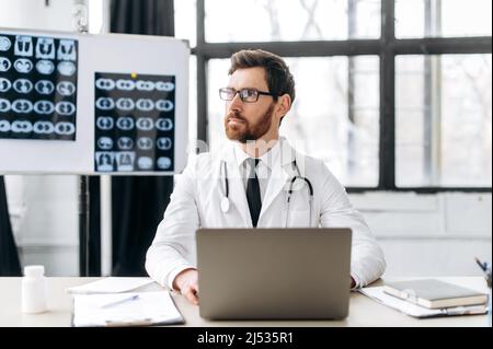 Médecine et concept de santé. Pensive caucasien médecin de médecine générale avec des lunettes, thérapeute, pulmonologieist, en uniforme médical, s'assoit sur le lieu de travail à l'hôpital, regarde le côté , pensant Banque D'Images