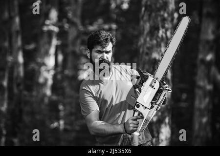 Beau jeune homme avec hache près de la forêt. Déforestation. Bûcheron dans les bois avec hache à tronçonneuse. Thème de l'agriculture et de la foresterie. Banque D'Images