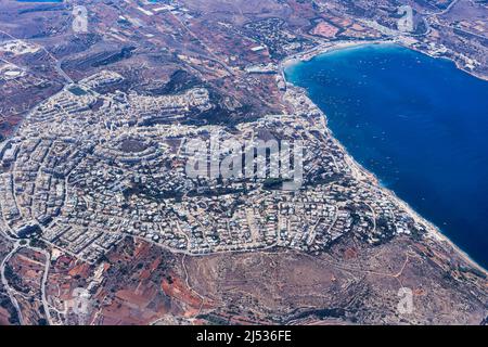 Île de Malte aérienne avec maisons et bâtiments autour de la baie de Mellieha et de la plage populaire de Ghadira visible. Banque D'Images