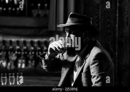 Dégustation et dégustation. Un homme avec une barbe tient un verre de brandy. Banque D'Images