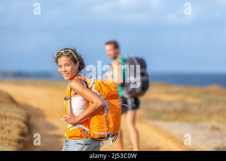 Jeune couple heureux randonnée ensemble dans la nature en plein air. Voyage aventure jeunes touristes marchant avec des sacs à dos en montagne au bord de l'océan Banque D'Images