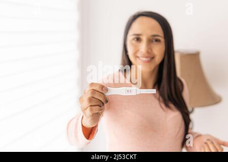 Gros plan de la main d'une femme latine tenant un test de grossesse Banque D'Images