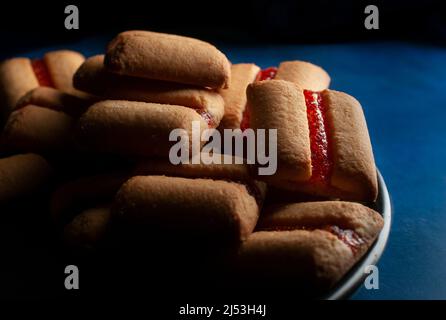 Une pile de barres de biscuits Strawberry sur une plaque noire au-dessus d'une table bleu foncé et d'une macro-photographie d'arrière-plan noir Banque D'Images