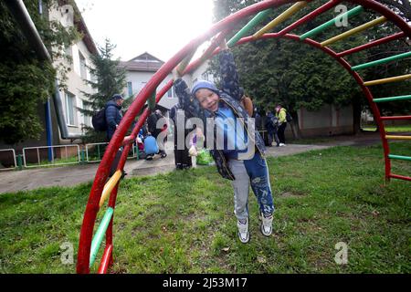 Un garçon s'accroche aux barreaux car les résidents des foyers nourriciers basés dans la région de Dnipropetrovsk sont sur le point de voyager par bus d'évacuation jusqu'à la frontière avec la Roumanie, Mukachevo, région de Zakarpattia, Ukraine occidentale, avril 16, 2022. Des milliers de personnes tentent de quitter l'est de l'Ukraine avant une offensive russe attendue dans la région. Selon les Nations Unies, plus de 10 millions de personnes auraient déjà fui leurs foyers en Ukraine à cause de l'invasion. Outre les 4,3 millions de personnes qui sont partis pour les pays voisins, 6,5 millions de personnes supplémentaires sont considérées comme des personnes déplacées Banque D'Images