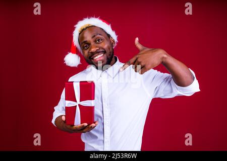homme latino-hispanique portant un chapeau santas sur fond rouge studio Banque D'Images