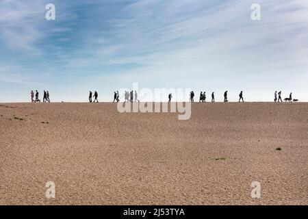 Marcheurs sur la plage de Folkestone en silhouette à l'horizon Banque D'Images