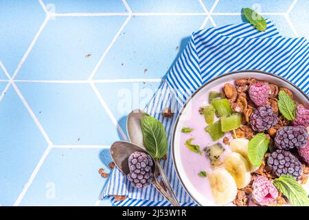 Petit-déjeuner d'été bol diététique sain avec yaourt, granola, fruits frais et baies, une portion avec une nuit de muesli avoine fruitée sur le sol carrelé illuminé Banque D'Images