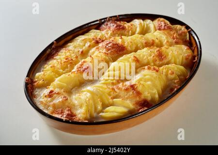 Du dessus de la casserole avec un appétissant gratin traditionnel au pomme de terre avec du fromage servi sur une table blanche dans la cuisine Banque D'Images