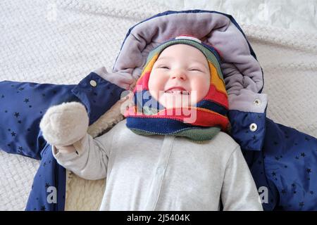 Bébé garçon heureux vêtu de vêtements chauds d'hiver est couché sur le lit Banque D'Images