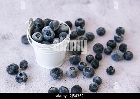 Bleuets congelés dans un petit seau sur fond de béton. Fond sain de fruits de saison biologiques. Aliments biologiques. Récolte, préparation de la nourriture pour gagner Banque D'Images