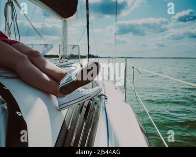 vue sur les jambes d'une jeune femme détendue, bronzer sur un yacht à voile pendant la voile Banque D'Images