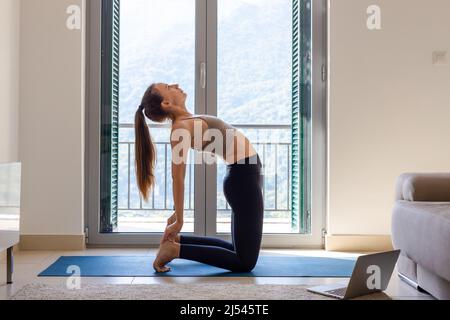 Jeune femme pratiquant le yoga en cours en ligne le matin à la maison Banque D'Images