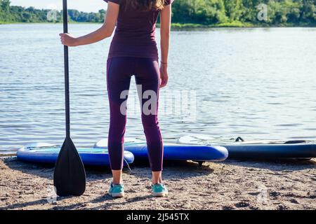 Montez le paddle-board sur un lac de mer calme, gros plan des jambes et des éclaboussures d'eau Banque D'Images