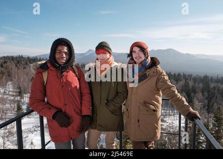 Portrait de deux jeunes hommes et d'une femme debout sur la plate-forme d'observation en haut de la montagne, regardant la caméra Banque D'Images