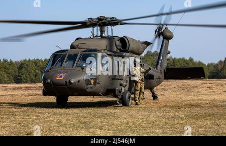 Un soldat affecté au bataillon de soutien général de l'aviation 1-214th, 12th Brigade de l'aviation de combat signale au personnel au sol qu'il peut s'approcher en toute sécurité de l'aéronef pendant un exercice d'entraînement d'une semaine dans la zone d'entraînement de Nadarzyce, en Pologne, le 25 mars 2022. La formation permet aux équipages aériens d'améliorer leurs compétences en matière de système d'armes à mitrailleuses M240H et d'améliorer leur aptitude à soutenir les opérations d'évacuation des blessés. L’ACR de 12th fait partie des unités attribuées au V corps, le Forward Deployed corps des Etats-Unis en Europe, qui travaille aux côtés des alliés de l’OTAN et des partenaires de sécurité régionaux pour la rp Banque D'Images