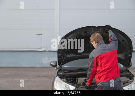 Un mécanicien a ouvert le capot pour inspecter l'état de la voiture. Inspection technique de la voiture, vue arrière Banque D'Images