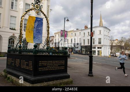 Un coureur passe devant un monument commémoratif de guerre de Crimée portant les couleurs du drapeau de l'Ukraine dans le centre-ville de Cheltenham, avril 2022. Banque D'Images