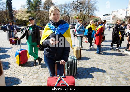 UZHHOROD, UKRAINE - le 19 AVRIL 2022 - Une femme enveloppée dans un drapeau ukrainien se tient dans une valise lors d'une procession pacifique depuis la place Petefi de Shandora Banque D'Images