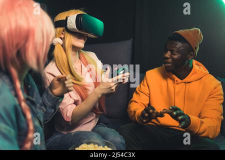 Groupe interracial d'amis de gamer essayant des lunettes de réalité virtuelle pour la première fois. Expérience partagée. . Photo de haute qualité Banque D'Images