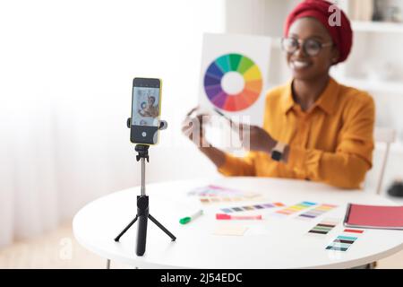 Mise au point sélective sur smartphone sur trépied, enregistrement femme noire Banque D'Images