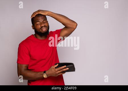 un homme africain cassé tenant un portefeuille vide Banque D'Images