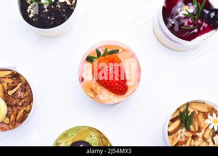 Cheesecake aux fraises avec des fraises fraîches sur le dessus et différentes saveurs de cheesecake sur la table en bois blanc Banque D'Images