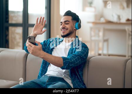 Jeune homme souriant dans un t-shirt bleu et avec un casque Banque D'Images