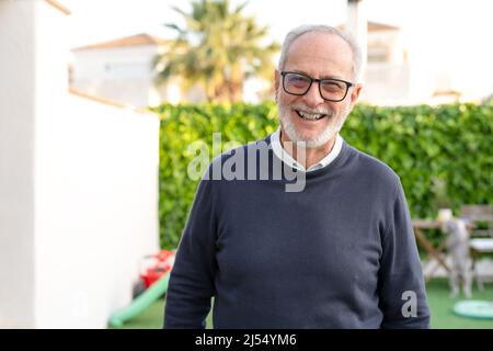 Homme aux cheveux gris, souriant, heureux de se tenir debout à l'extérieur Banque D'Images