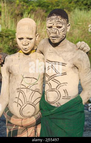 Surma man and boy avec peintures corps debout dans la rivière, la vallée de la rivière Omo, Kibish, Ethiopie Banque D'Images