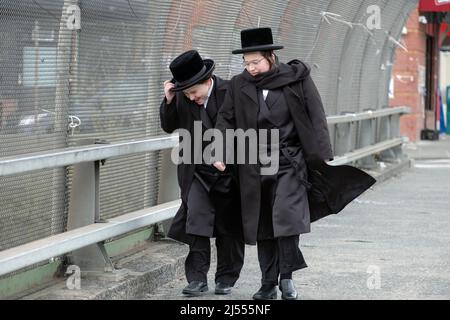 Deux jeunes juifs ultra-orthodoxes dans leurs vêtements de vacances, marchez sur l'avenue Lee lors d'un jour de printemps venteux. À Williamsburg, Brooklyn, New York. Banque D'Images