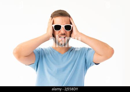 Jeune homme sur fond blanc faisant une expression effrayée Banque D'Images