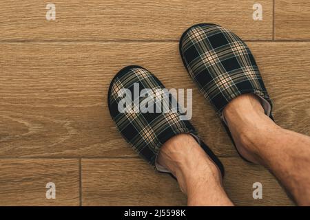 Pieds mâles portant des pantoufles en tissu écossais dans la salle de bains, vue du dessus avec espace pour les copies Banque D'Images