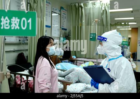 (220420) -- SHANGHAI, le 20 avril 2022 (Xinhua) -- Un travailleur médical parle à un membre de la famille d'un patient à la salle d'urgence de l'hôpital Minhang affilié à l'Université Fudan de Shanghai, en Chine orientale, le 20 avril 2022. Afin de mieux prendre en charge les patients gravement malades lors de la récente épidémie de COVID-19 à Shanghai, l'hôpital Minhang affilié à l'Université Fudan a réorganisé son équipe d'urgence avec 31 médecins et plus de 100 infirmières.Sun Keyu, le directeur du service des urgences, qui possède plus de 20 ans d'expérience en traitement d'urgence, dirige l'équipe à s'en tenir Banque D'Images