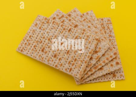 Matzo pain sans levain pour Pesach, fête juive de la Pâque. Pains plats Matzah isolés sur fond jaune. Banque D'Images