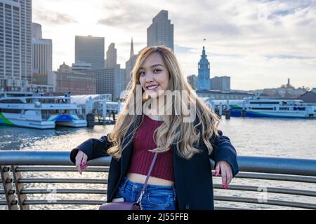 Jeune femme souriante avec San Francisco Skyline et Marina en arrière-plan | Voyage local style de vie Banque D'Images