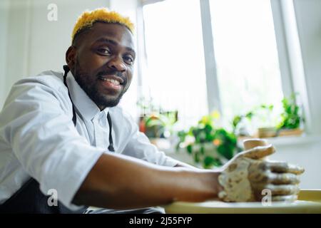 Portrait d'un homme brésilien latino-hispanique positif qui fait un pot en céramique sur la roue de poterie Banque D'Images