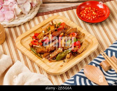 Tofu séché frit au poisson séché au piment dans un bol avec une cuillère et des baguettes isolées sur le côté mat vue sur la table en bois de la nourriture de taïwan Banque D'Images